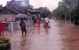Warga menyusuri jalanan yang banjir dengan rakit bambu sederhana